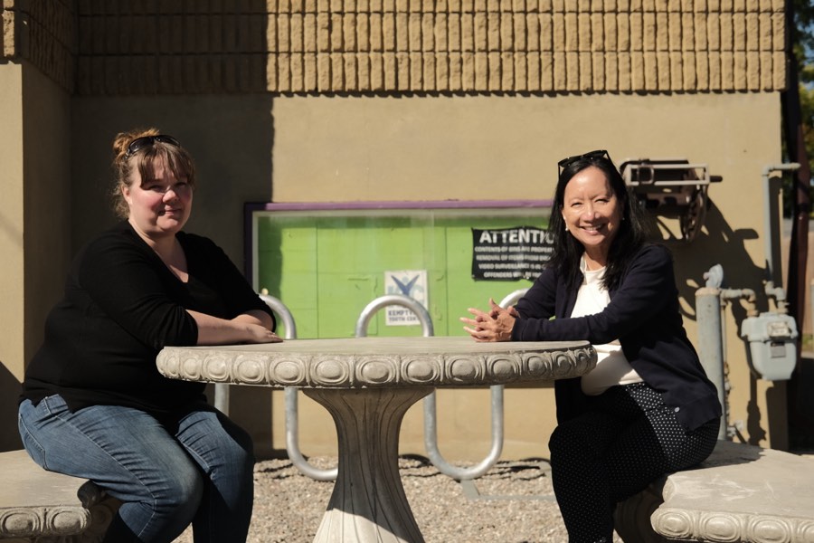Two community members sitting together at an outdoor table outside the Kemptville Youth Centre