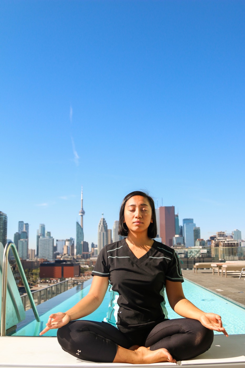 A QuickRN-trained healthcare worker in scrubs practising mindfulness on a Toronto rooftop overlooking the city skyline