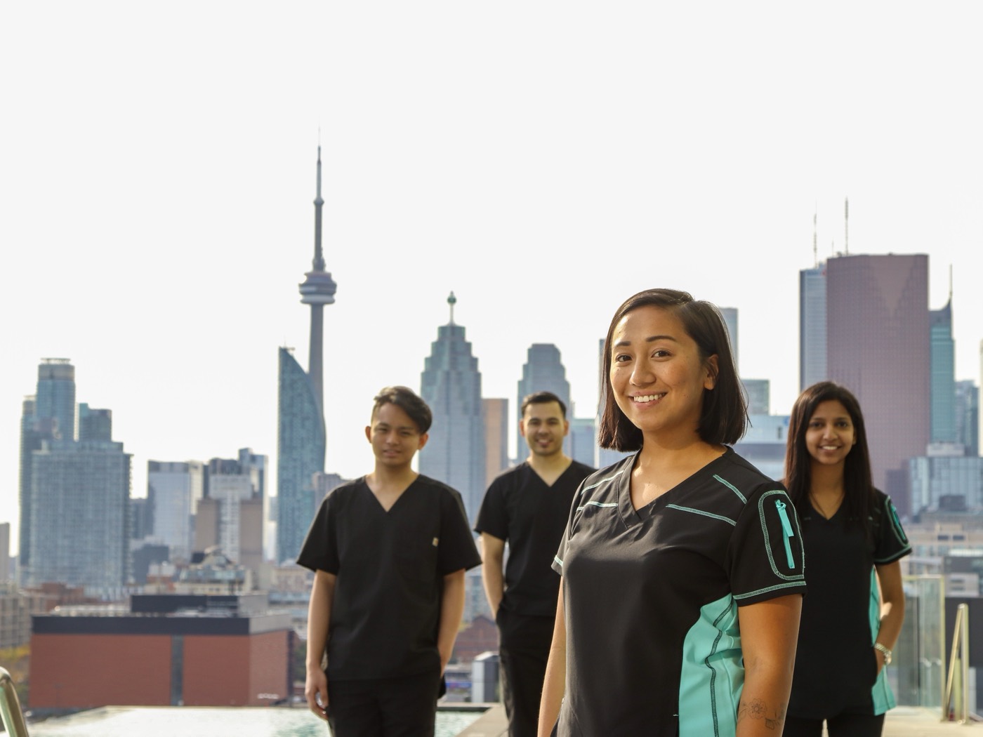 A QuickRN-trained healthcare worker in scrubs sitting in meditation on a Toronto rooftop with the CN Tower and downtown skyline behind her